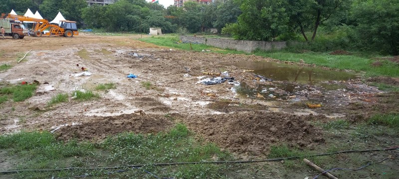 An area previously dug out for an artificial pond has been filled in, with a large amount of debris and solid waste still scattered around the site